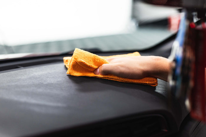 Person cleaning a car with Opti-Coat Protectant Plus and a orange microfiber.