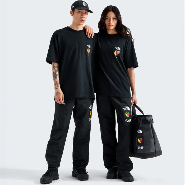 Two people wearing matching black outfits with logos, standing against a white background.