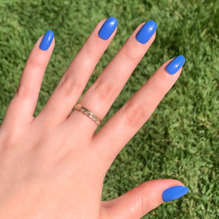 Hand with Blue Canoe | Round | Short medium denim blue press-on nails in classic round shape on natural skin tone outdoors