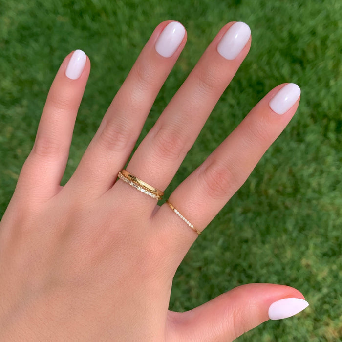 Hand with sheer pink nails in an extra short round shape wearing gold rings from CCT | Round | Extra Short press-on set