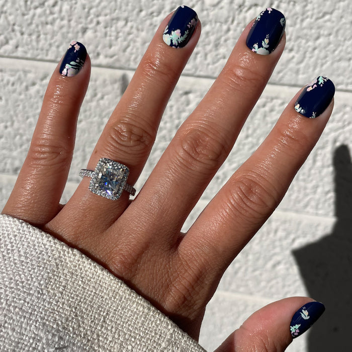 Hand with Micro Floral - Press-Ons | Extra Short | Squoval featuring delicate pastel flowers on dark navy base for spring manicure