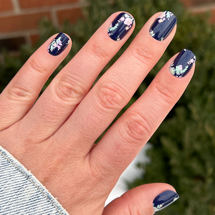 Hand with Micro Floral - Press-Ons | Extra Short | Squoval featuring delicate spring floral design on dark navy manicure by Olive and June