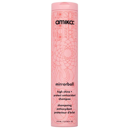 A tall, cylindrical pink bottle of amika mirrorball high shine protectant antioxidant shampoo, featuring a pink cap and a floral line-art pattern on a white background Hair Care Canada