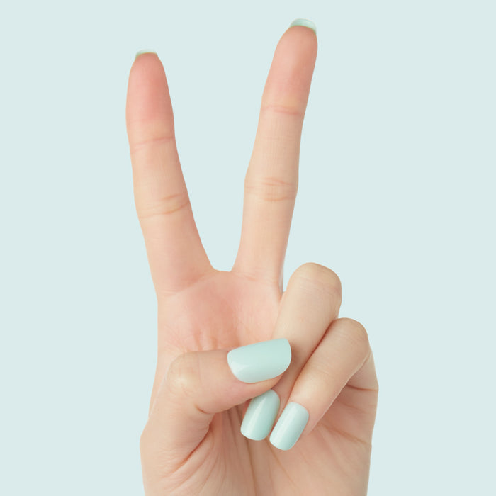 Hand showing peace sign with Sleeping Bag | Squoval | Short mint green press-on nails against pale blue background