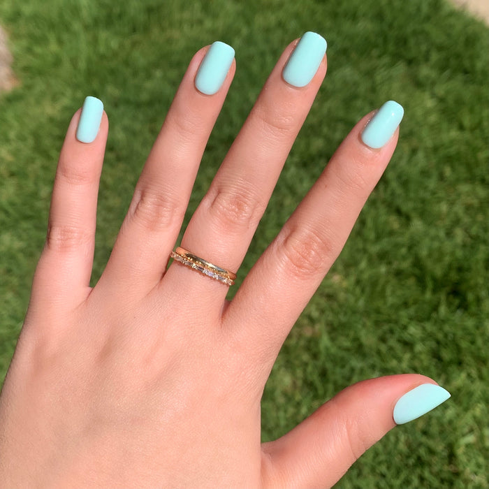 Hand sporting Sleeping Bag | Squoval | Short mint pastel green press-on nails outdoors with natural sunlight and gold ring