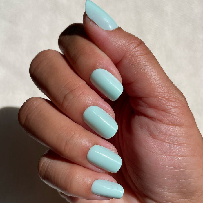 Hand showcasing Sleeping Bag | Squoval | Short mint pastel green press-on nails in bright natural light