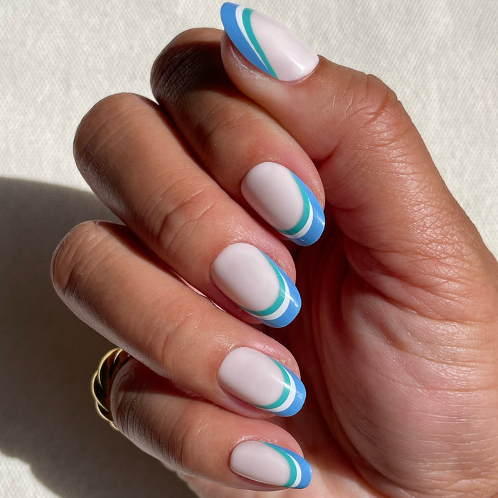 Hand with Triple French | Round | Short press-on mani featuring blue and green triple striped tips on pale base