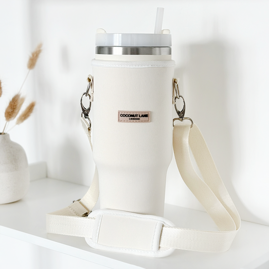 White tumbler with a straw in a cream Coconut Lane carry case, shown on a white shelf.