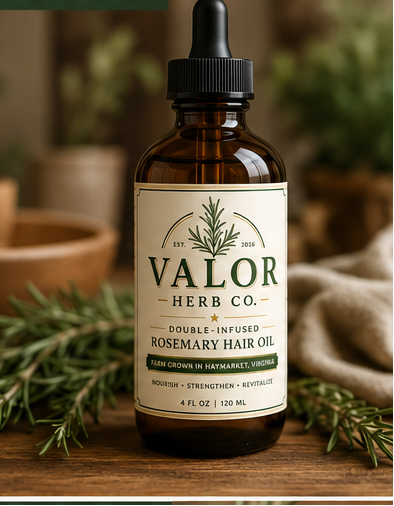 Bottle of Valor Herb Co. Rosemary Hair Oil with a dropper on a wooden surface with greenery.