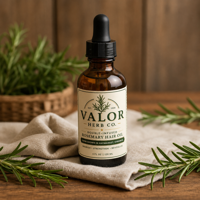 Bottle of Valor Herb Co. rosemary hair oil on a wooden surface with rosemary leaves.